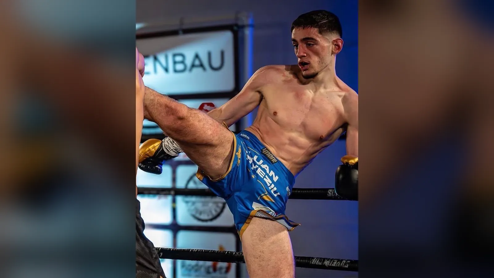 Luan Kryeziu tritt im Boxring hoch zu; auf seiner blauen Kampfhose stehen sein Name und Sponsorenlogos