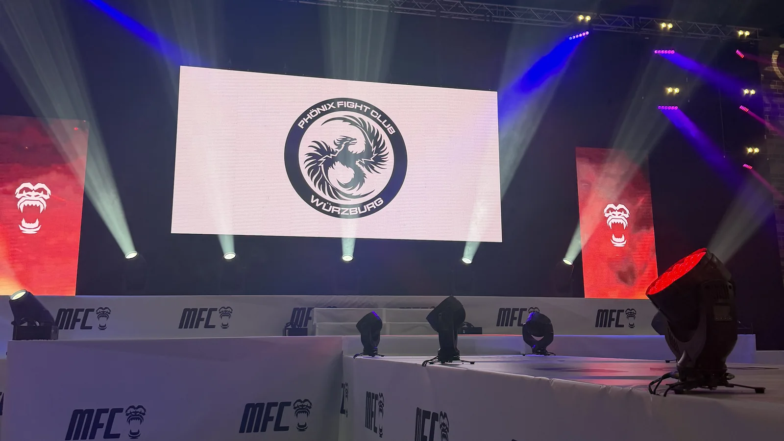 Einlauf-Bühne bei MFC 55 in Würzburg: Das Logo des Phönix Fight Club leuchtet auf der großen Leinwand, davor die Bande mit MFC-Logos